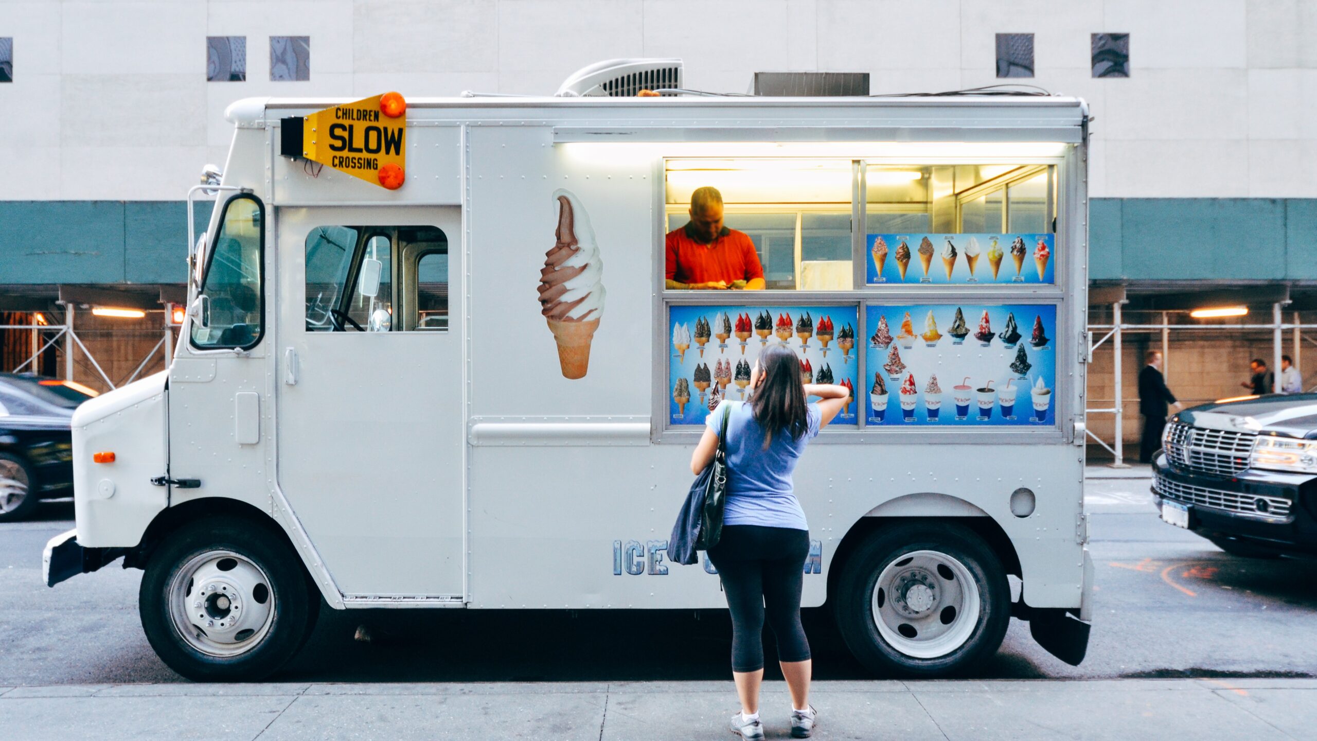 Kobieta zamawia lody w mobilnej budce food trucka.